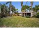 Green backyard with tropical landscaping and home view at 311 15Th Ave, Indian Rocks Beach, FL 33785
