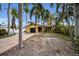 House exterior, showcasing a yellow house with palm trees and a brick driveway at 311 15Th Ave, Indian Rocks Beach, FL 33785
