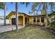 A yellow house with a dark garage door and lush landscaping at 311 15Th Ave, Indian Rocks Beach, FL 33785
