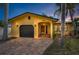 Front view of a yellow house with a dark garage door, and a brick driveway at 311 15Th Ave, Indian Rocks Beach, FL 33785