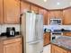 Stainless steel refrigerator surrounded by wood cabinets, granite countertops, white backsplash, and modern appliances at 3647 Fawnmist Dr Dr, Wesley Chapel, FL 33544