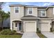 Townhouse exterior featuring a two-car garage, neutral stucco and well-maintained landscaping at 7055 Summer Holly Pl, Riverview, FL 33578