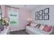 Bright bedroom featuring pastel pink walls, gray carpet, a daybed, and decorative floral art at 750 Steel Dr, Apollo Beach, FL 33572