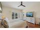 View of the main bedroom with a TV, ceiling fan, and access to the balcony with treed views at 7532 Marsh Orchid Cir # 8-201, Bradenton, FL 34203
