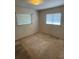 This is a bedroom with two windows, a light fixture, and worn carpeting at 10120 N Aster Ave, Tampa, FL 33612