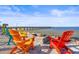 Beachfront view with colorful Adirondack chairs by a stone fire pit near a wooden pier at 1021 Seagrape Dr, Ruskin, FL 33570