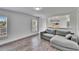 Living area with grey sectional and wood-look floors at 11206 Silver Fern Way, Riverview, FL 33569