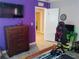 A bedroom featuring purple accent walls, a wooden dresser, and a corner gaming setup at 12368 70Th St, Largo, FL 33773