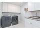 Well-lit laundry room with modern washer and dryer, cabinetry, and granite countertops at 12625 Horseshoe Bend Dr, Lithia, FL 33547