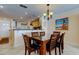 Cozy dining area with a modern chandelier, adjacent to a kitchen with light wood cabinets and white tile flooring at 13500 Gulf Blvd # 702, Madeira Beach, FL 33708