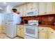 Well-lit kitchen featuring updated appliances, warm cabinets, and granite countertops at 13500 Gulf Blvd # 702, Madeira Beach, FL 33708