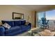 Inviting living room with comfortable blue seating, stylish mirror, and access to a balcony with ocean views at 13500 Gulf Blvd # 702, Madeira Beach, FL 33708