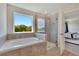 Bright bathroom featuring a soaking tub under a window and a glass-enclosed shower at 13526 Palmera Vista Dr, Riverview, FL 33579