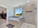 Bright bathroom featuring a soaking tub under a window and a glass-enclosed shower at 13526 Palmera Vista Dr, Riverview, FL 33579