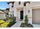 Inviting front entrance with a charming black door, neutral exterior, and lush landscaping at 13526 Palmera Vista Dr, Riverview, FL 33579