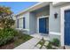 View of a light blue house showcasing a neat front garden, blue door and shutters at 20327 Merry Oak Ave, Tampa, FL 33647