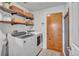 Functional laundry room featuring modern appliances, overhead shelving with decorative baskets and a door to the exterior at 24121 Landing Dr, Lutz, FL 33559