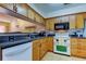 Well-lit kitchen featuring wood cabinets, black countertops, white appliances, and a pass-through to the adjacent room at 2559 Stony Brook Ln, Clearwater, FL 33761