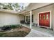 Inviting front porch with swing seating, a koi pond, and a charming entrance with a red double-door at 26890 Hiawatha Blvd, Brooksville, FL 34601