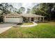 Inviting home with a lush green lawn, mature trees, and a charming walkway leading to the front entrance at 26890 Hiawatha Blvd, Brooksville, FL 34601