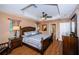 Spacious main bedroom featuring a tray ceiling, ceiling fan, wood floors, and en suite bathroom at 26890 Hiawatha Blvd, Brooksville, FL 34601