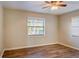 Spacious bedroom with wood-look floors, window with blinds, and ceiling fan at 3241 Rogue St, North Port, FL 34291