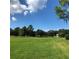 Expansive green space with mature trees and a small structure in the background under a clear sky at 36750 Us Highway 19 N # 17-111, Palm Harbor, FL 34684