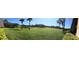 Panoramic view of lush green lawn and pond surrounded by trees, creating a serene and inviting atmosphere at 36750 Us Highway 19 N # 17-111, Palm Harbor, FL 34684