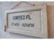 Decorative sign with coordinates for Cortez, FL in a rustic, antique style at 4212 126Th W St # 401, Cortez, FL 34215