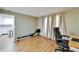 Bright bedroom featuring wood floors, a Concept 2 rower, natural light, and a home office setup at 4917 Puritan Cir, Tampa, FL 33617