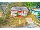 Overhead shot of a single-story white and red trimmed home with a healthy yard, driveway, and surrounding tree coverage at 5308 Ben Hur Dr, St Petersburg, FL 33708