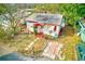 Aerial view of a white single-story house with red trim surrounded by lush greenery and a well-maintained lawn at 5308 Ben Hur Dr, St Petersburg, FL 33708