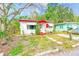 Inviting single-story home with white walls and red trim surrounded by lush landscaping and a well-maintained lawn at 5308 Ben Hur Dr, St Petersburg, FL 33708