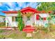 Charming single-story home with a red trimmed porch, white walls, and a garden of potted plants in the front yard at 5308 Ben Hur Dr, St Petersburg, FL 33708