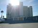 Multi-story condominium building with parking lot, garages, and palm trees on a sunny day at 7000 Beach Plz # 805, St Pete Beach, FL 33706