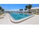 Community pool with lounge chairs surrounded by tropical palm trees and the ocean at 7300 Sunshine Skyway S Ln # 202, St Petersburg, FL 33711