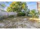 Backyard is enclosed by a wood fence with shade trees, offering privacy and potential at 9121 Prosperity Ln, Port Richey, FL 34668