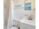 All-white bathroom with tiled walls and floors, featuring a shower with a curtain and a vanity with a mirror at 9121 Prosperity Ln, Port Richey, FL 34668