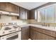 Traditional kitchen featuring wood cabinets, white countertop, classic appliances, and a window above the sink at 9121 Prosperity Ln, Port Richey, FL 34668