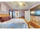 Bedroom with a wood frame bed, ceiling fan, tv and a view into the bathroom at 9417 Star Gazer Ln, Riverview, FL 33578