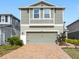 Close-up of a two-story home featuring gray siding, a brick driveway, and mature landscaping at 11616 Little River Way, Parrish, FL 34219