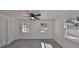 Bedroom with gray wood-look flooring, a ceiling fan, and three windows for ample natural light at 1303 E New Orleans Ave, Tampa, FL 33603