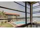 View from the enclosed lanai showcasing the community pool, surrounding buildings, and water views at 19701 Gulf Blvd # 328, Indian Shores, FL 33785