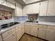 Compact kitchen with white cabinets, tile backsplash, and stainless steel sink at 2100 World Parkway Blvd # 56, Clearwater, FL 33763