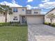Two-story house with gray roof and stone accents, showcasing a three-car garage at 2302 Village Amble Loop, Lutz, FL 33558