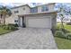 Two-story house with gray roof, stone accents, and a three-car garage at 2302 Village Amble Loop, Lutz, FL 33558