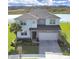 Two-story house with gray roof and stone accents, showcasing a three-car garage and well-manicured lawn at 2302 Village Amble Loop, Lutz, FL 33558