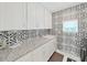 Laundry room with white cabinets, granite countertops, and patterned backsplash at 2302 Village Amble Loop, Lutz, FL 33558