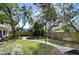 Lush backyard with a stone pathway, grassy areas, mature trees, and a wooden fence for privacy and security at 3621 S Belcher Dr, Tampa, FL 33629