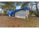 Side and rear view of home needing repair covered by a tarp, yard covered in leaves at 3623 Whittier St, Tampa, FL 33619